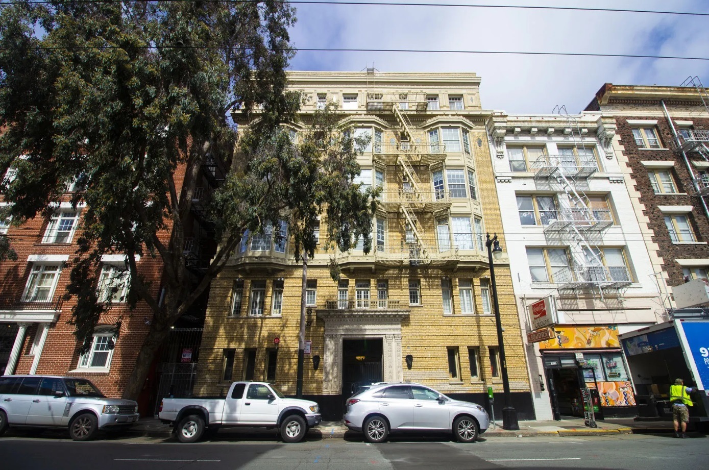 A street view of a row of buildings with cars parked in front.